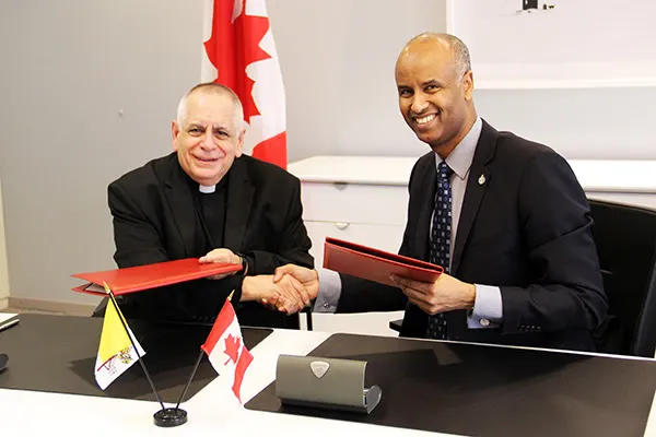 Mons. Bob Vitillo e Ahmed Hussen | Monsignor Bob Vitillo e il ministro canadese per i rifugiati Ahmed Hussen siglano l'accordo | ICMC