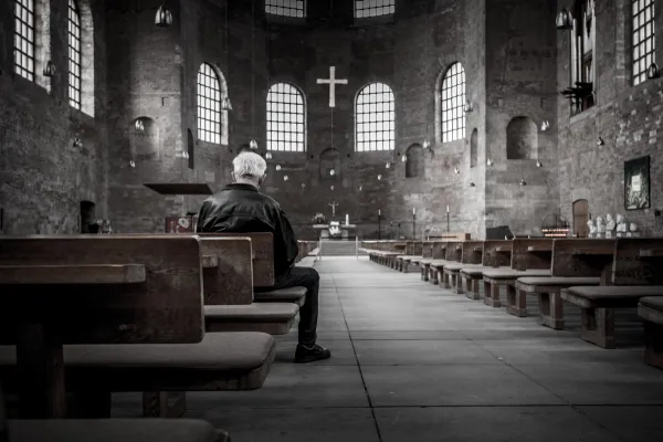 Un uomo in preghiera davanti ad una croce in una chiesa / pxhere - public domain