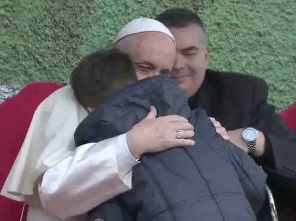 Papa Francesco a San Paolo della Croce | Papa Francesco abbraccia il piccolo Emanuele, nell'incontro con i bambini alla parrocchia di San Paolo della Croce. Sullo sfondo, il parroco Don Roberto Cassano, San Paolo della Croce, Roma, 15 aprile 2018 | Vatican Media - Youtube